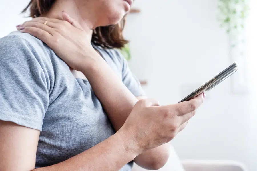 Tech neck from looking down at phones causing chronic neck strain in Yorktown VA